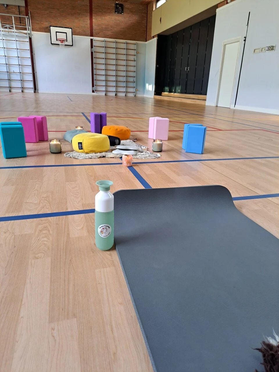 Volledige yogales opstelling met kussens, kaarsen, yogamat en waterfles voor een serene ervaring